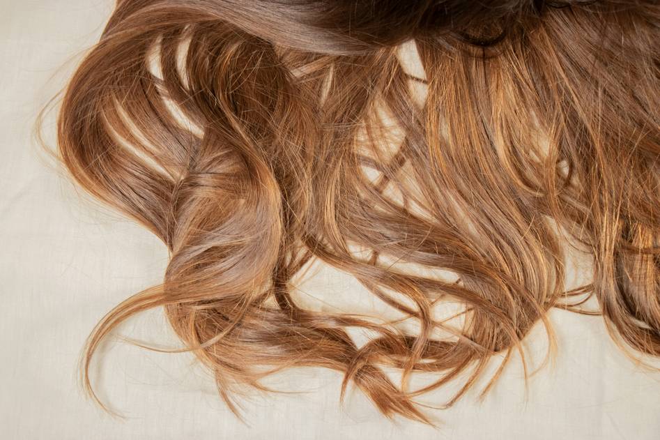 Blogger holding strands of highlighted hair while reviewing products
